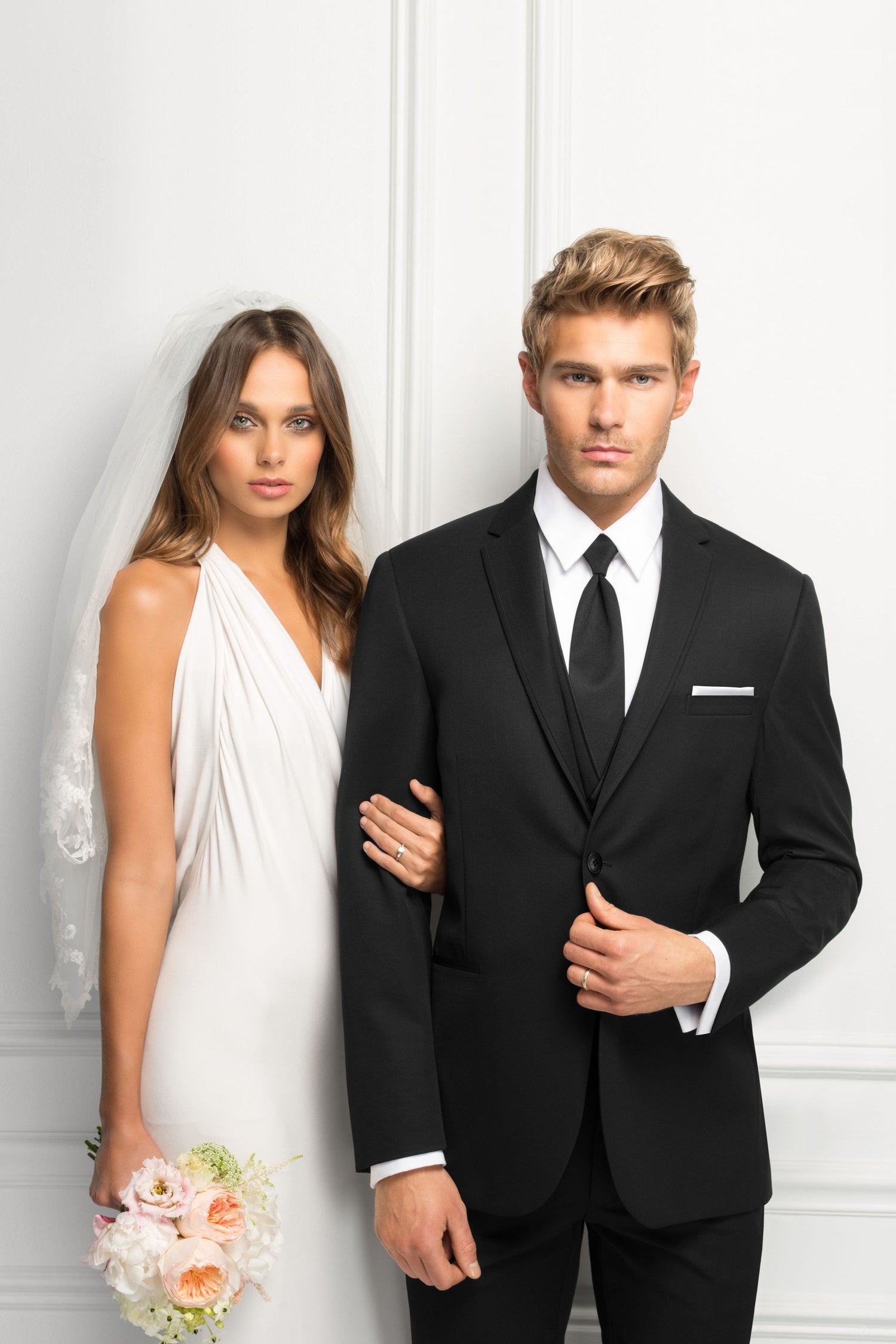 Bride and groom standing side by side in bridal gown and tuxedo